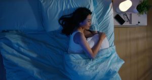 woman sleeping on her side, dark blue room