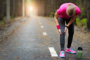 woman bending over on a road, sore knee after running