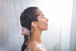 Woman with brown hair, shampooing in a shower