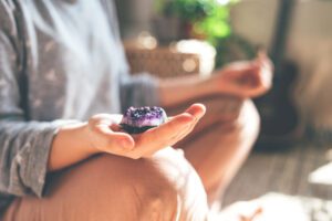 person meditating with purple crystal in hand.