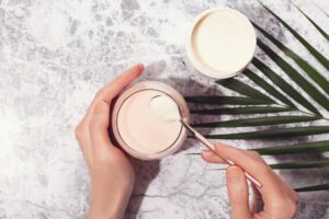 top down image of woman scooping cream out of container, leaf