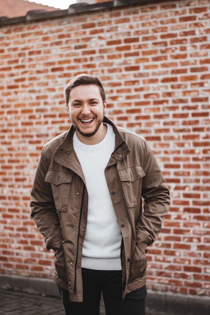 Man in front of brick wall, jacket on