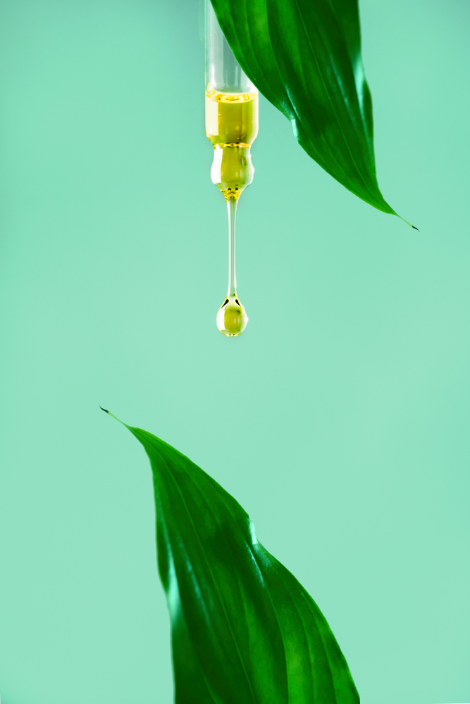 Vitamin E cream dropper green background vertical